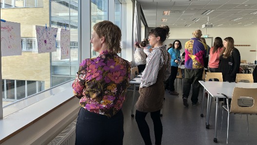 Några personer står och betraktar upphängda teckningar.