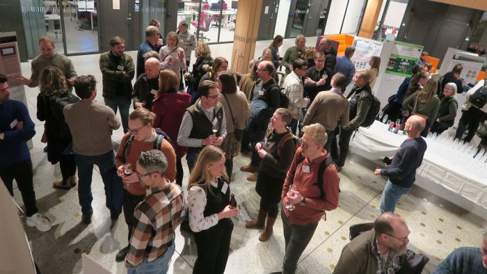 Många människor står i en hall och pratar med varandra, bilden tagen snett ovanifrån