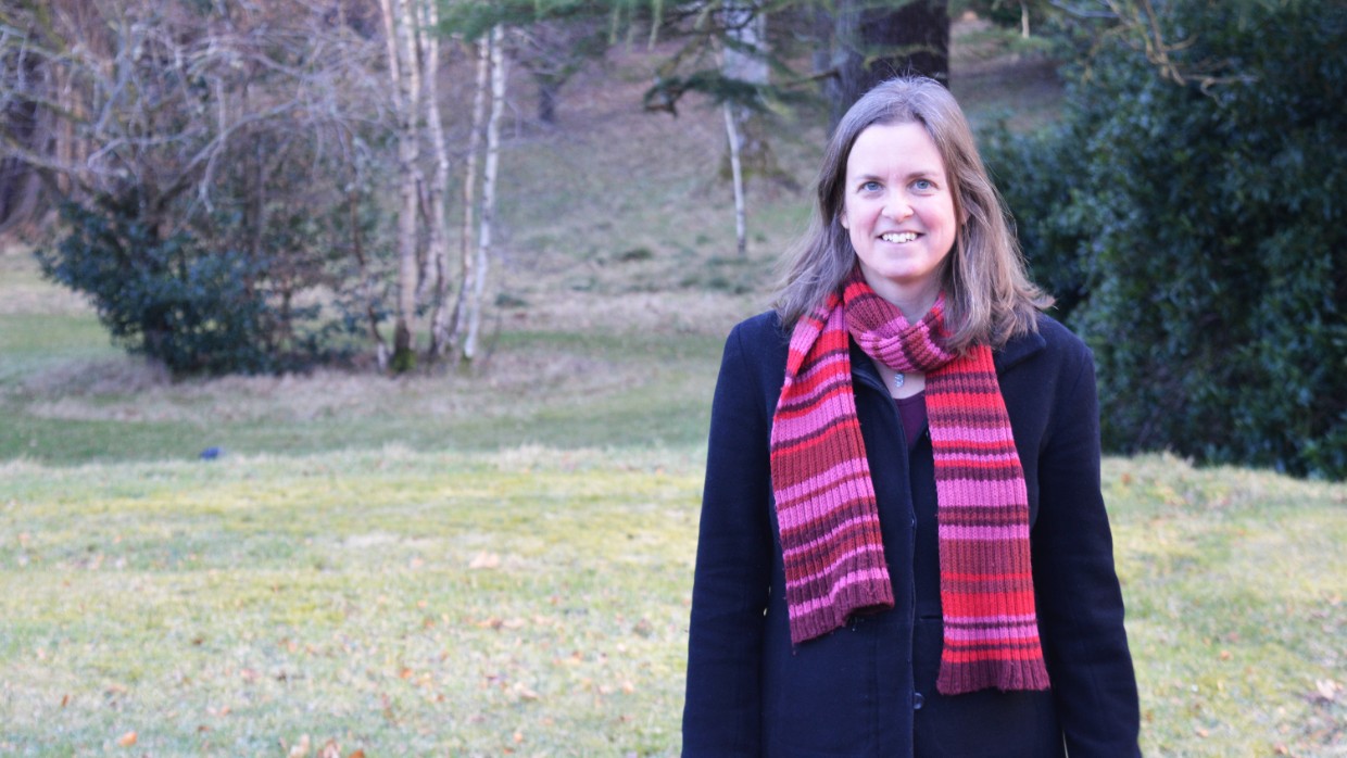 A woman in a dark coat with a red scarf. Photo.