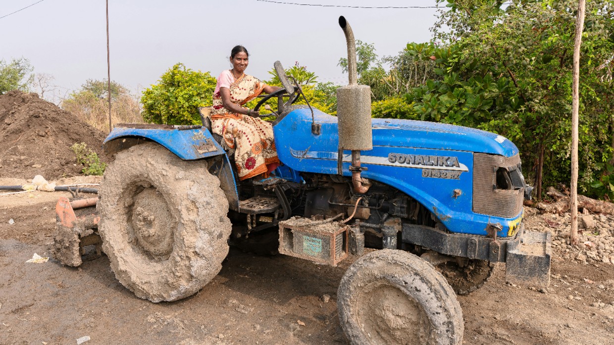 An Indian woman is sitting on a tractor. Photo.