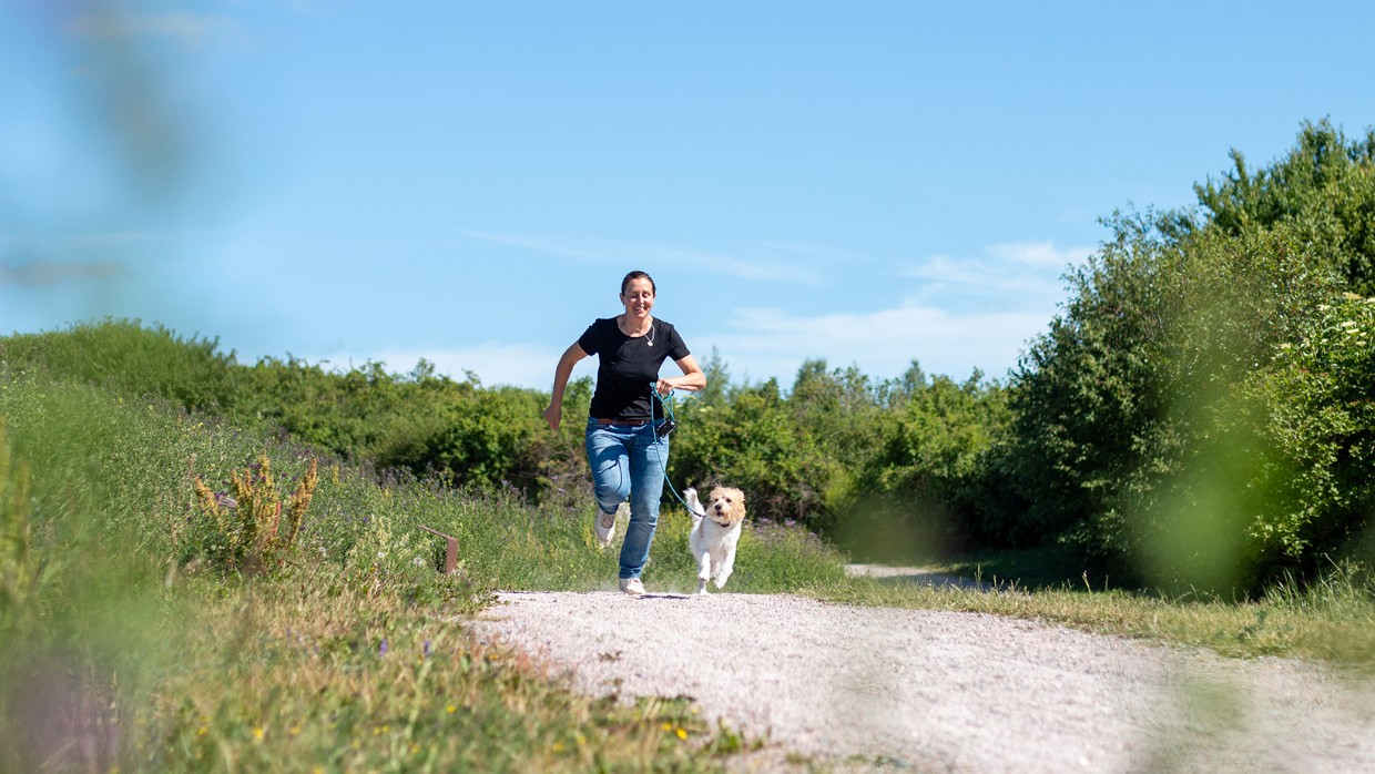 En kvinna och en hund springer tillsammans. Foto. 