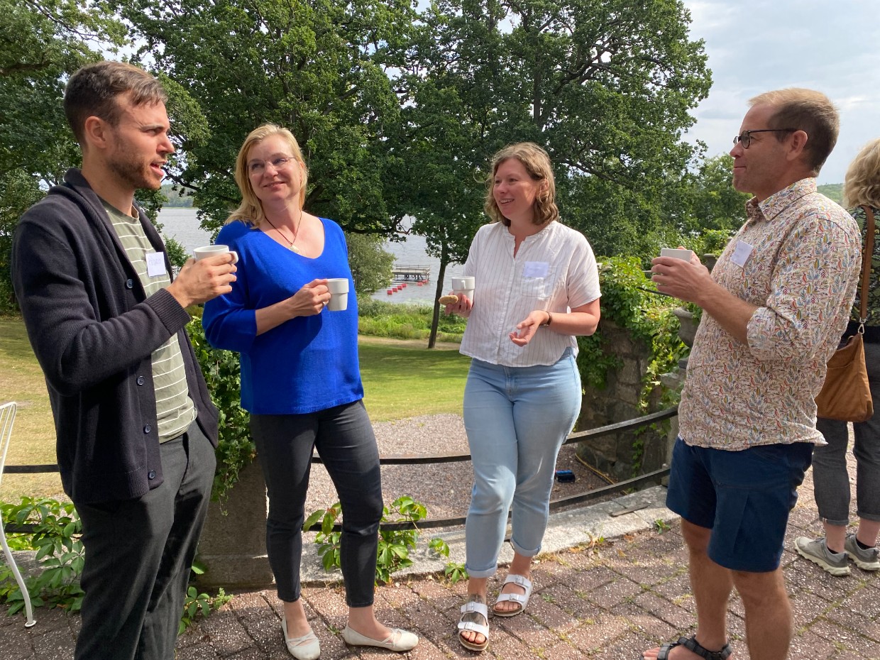 Two men and two women are standing and talking in a beautiful outdoor setting. Photo.